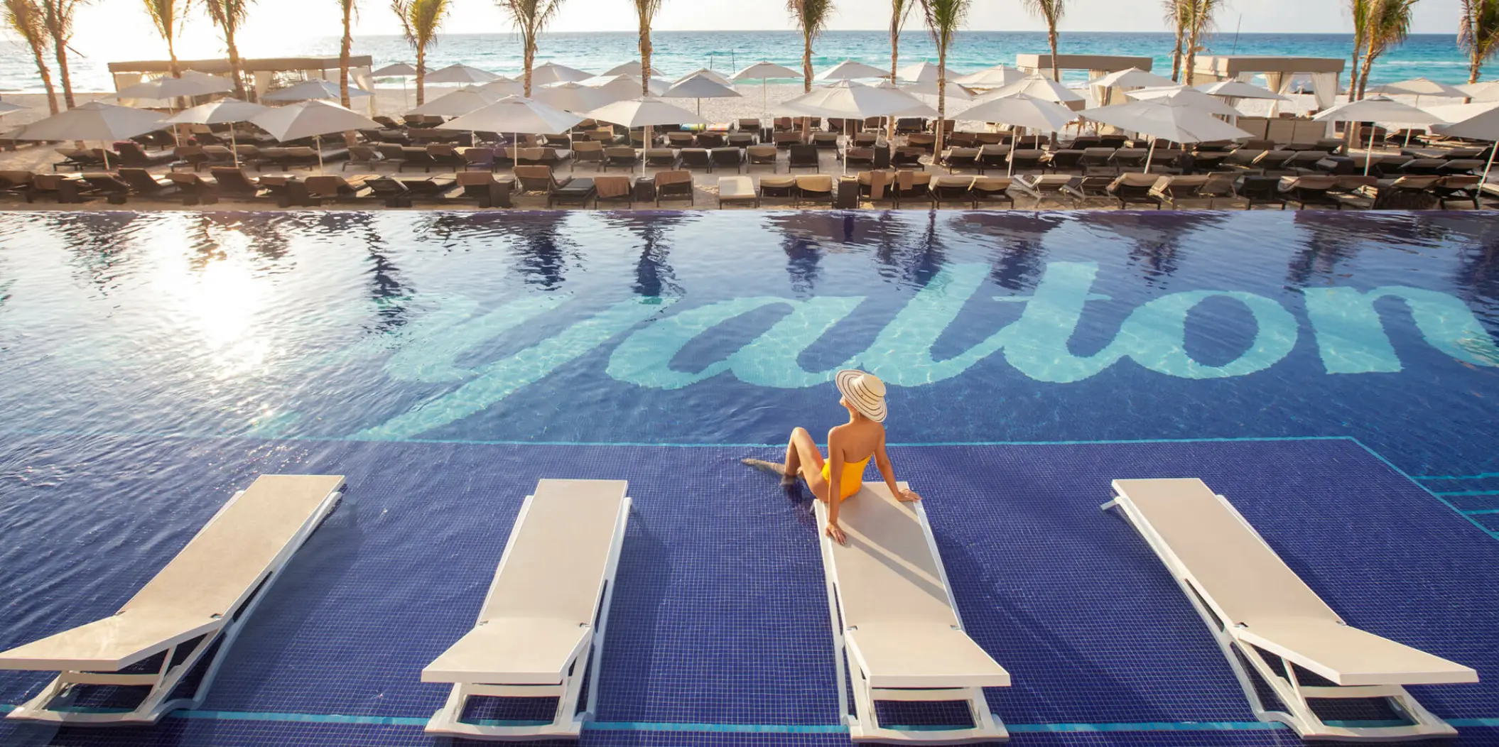 Main pool with submerged loungers and beachfront umbrellas at Royalton CHIC Cancun, Cancun