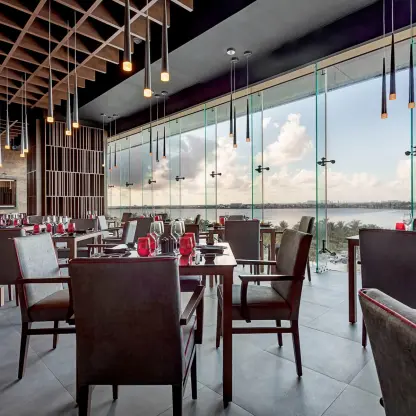 Modern indoor restaurant with floor-to-ceiling windows overlooking the water at Royalton CHIC Cancun