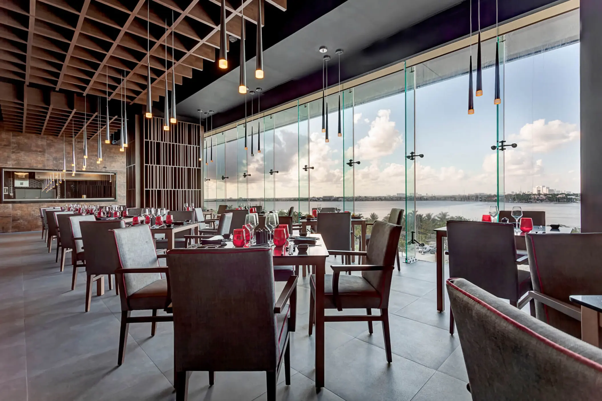 Modern indoor restaurant with floor-to-ceiling windows overlooking the water at Royalton CHIC Cancun