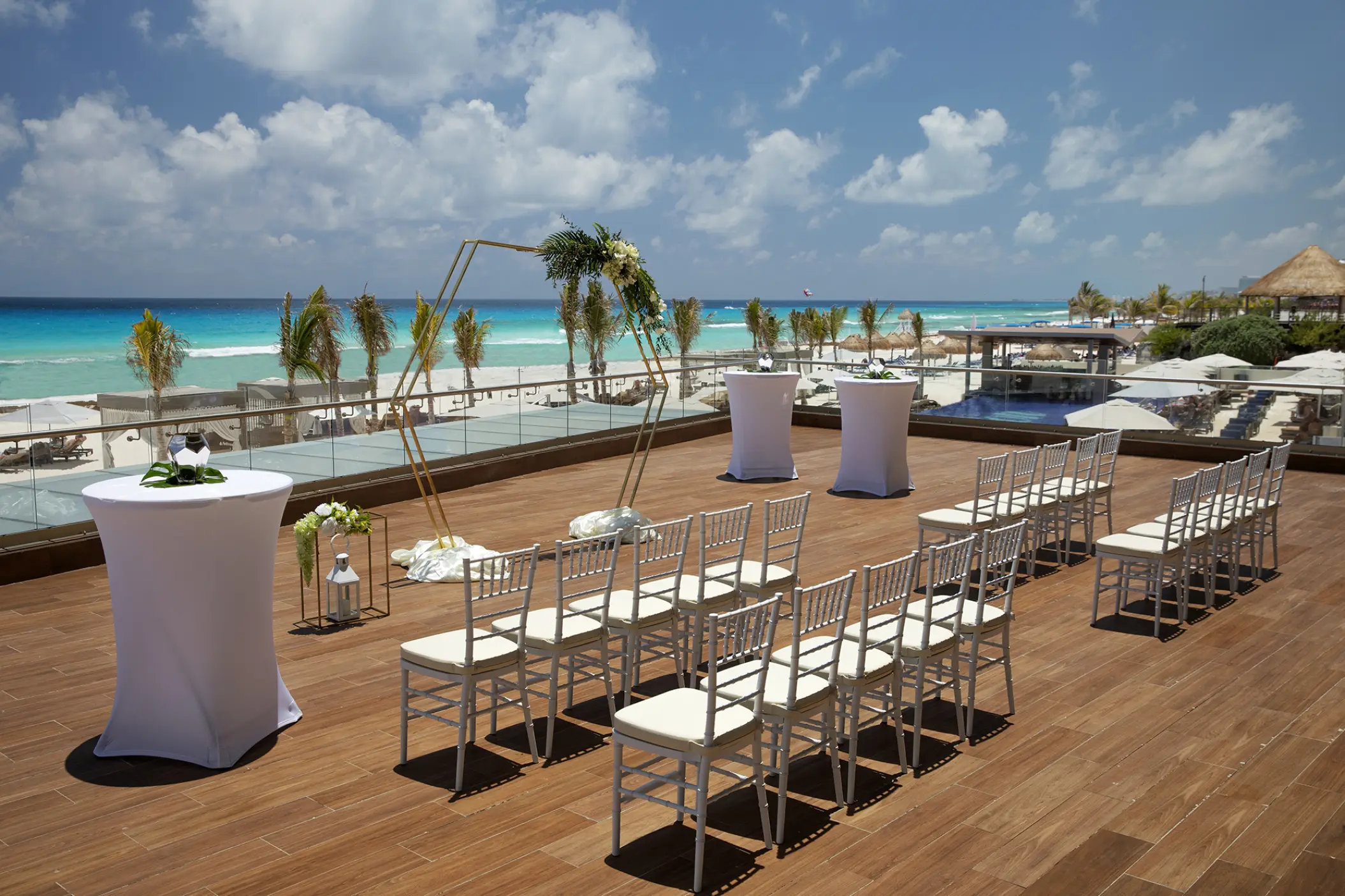 Sunrise Terrace wedding ceremony setup with white chairs and a gold arch at Royalton CHIC Cancun