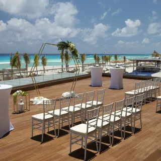 Sunrise Terrace wedding ceremony setup with white chairs and a gold arch at Royalton CHIC Cancun