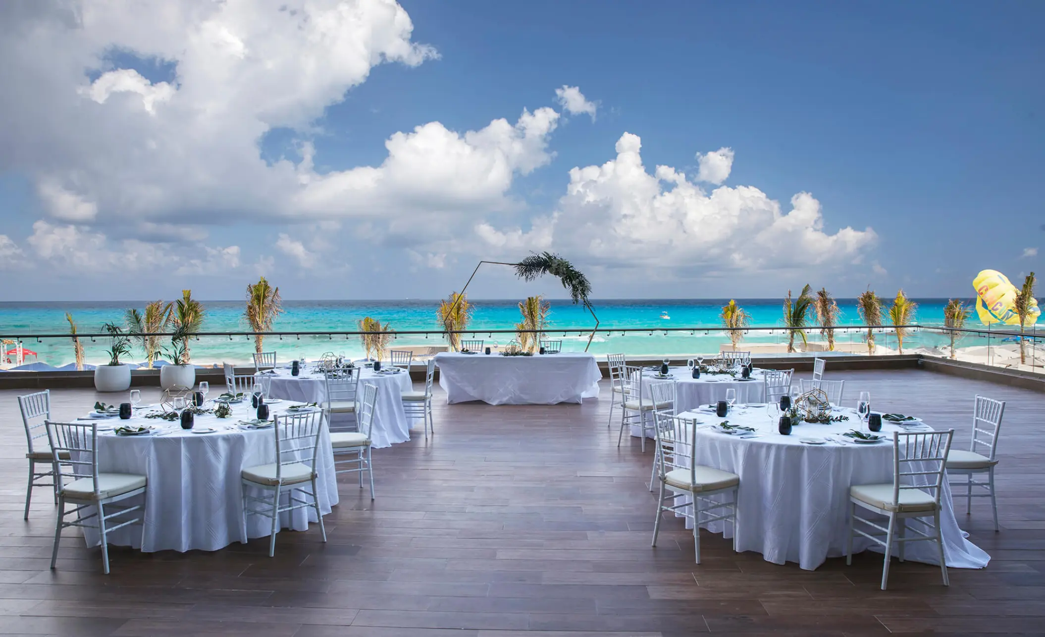 Terrace wedding reception with round tables overlooking the ocean at Royalton CHIC Cancun