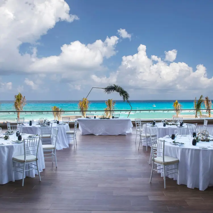Terrace wedding reception with round tables overlooking the ocean at Royalton CHIC Cancun