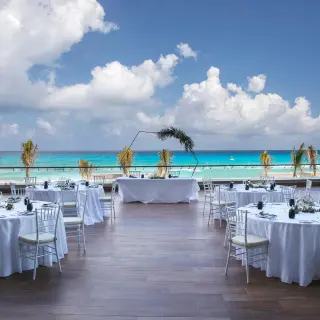 Terrace wedding reception with round tables overlooking the ocean at Royalton CHIC Cancun