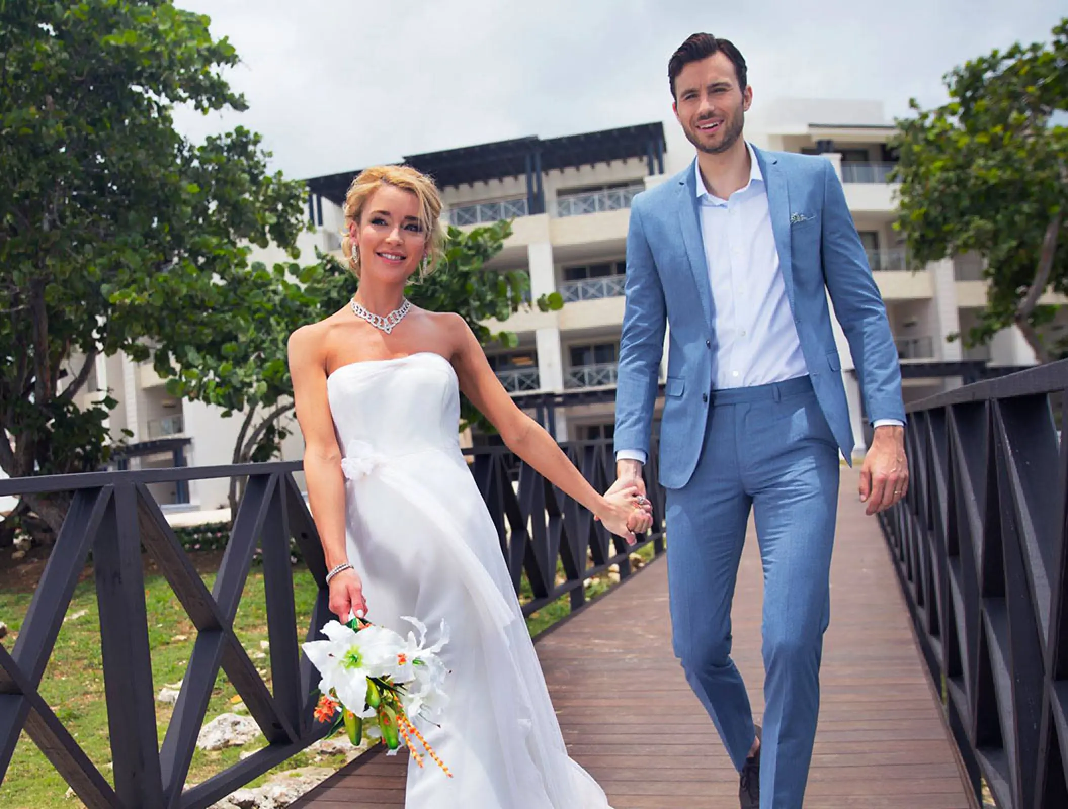 Bride and groom walking across a wooden bridge at Royalton Negril