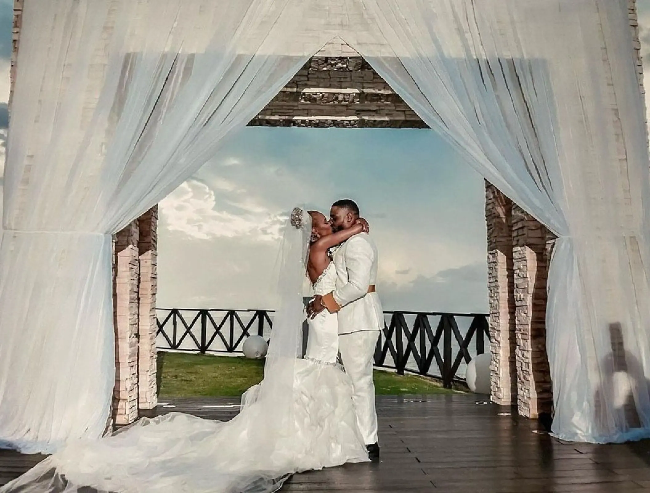 The couple kissing under a draped gazebo during their wedding at Royalton Negril