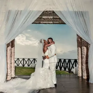 The couple kissing under a draped gazebo during their wedding at Royalton Negril