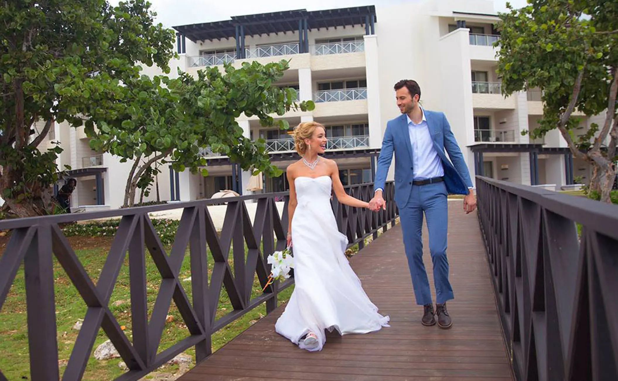 Bride and groom walking across a wooden bridge at Royalton Negril, Jamaica