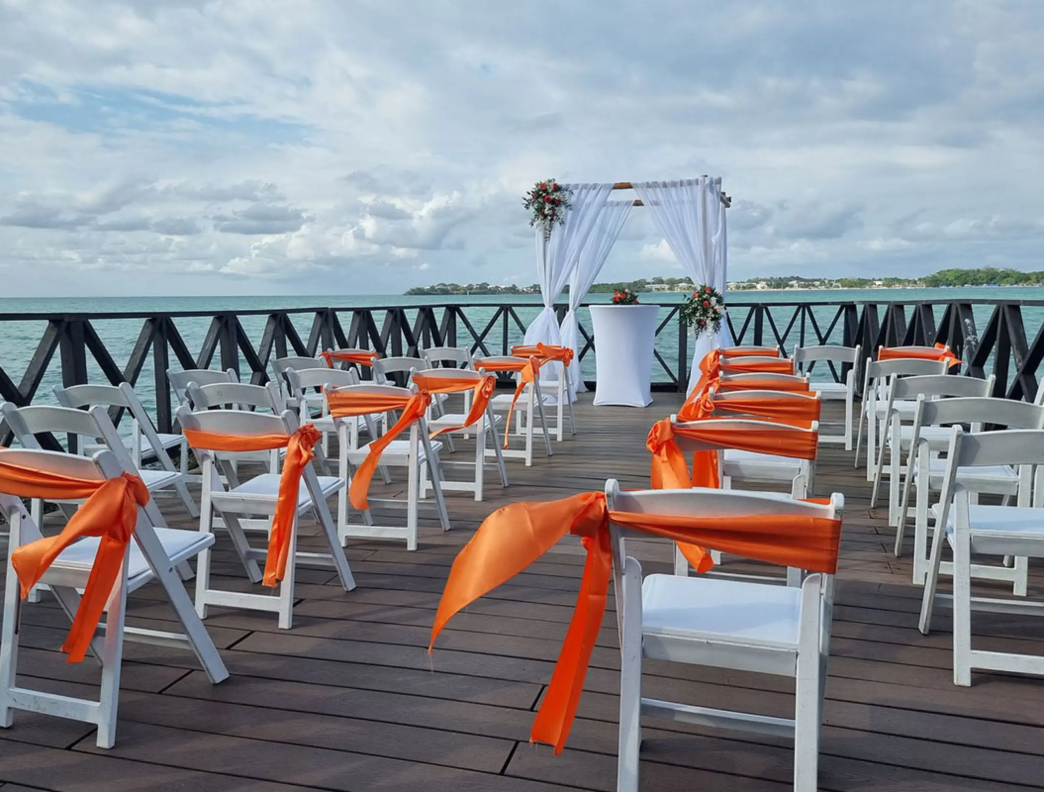 Chairman Ocean Pier wedding ceremony at Royalton Negril with white chairs and orange sashes