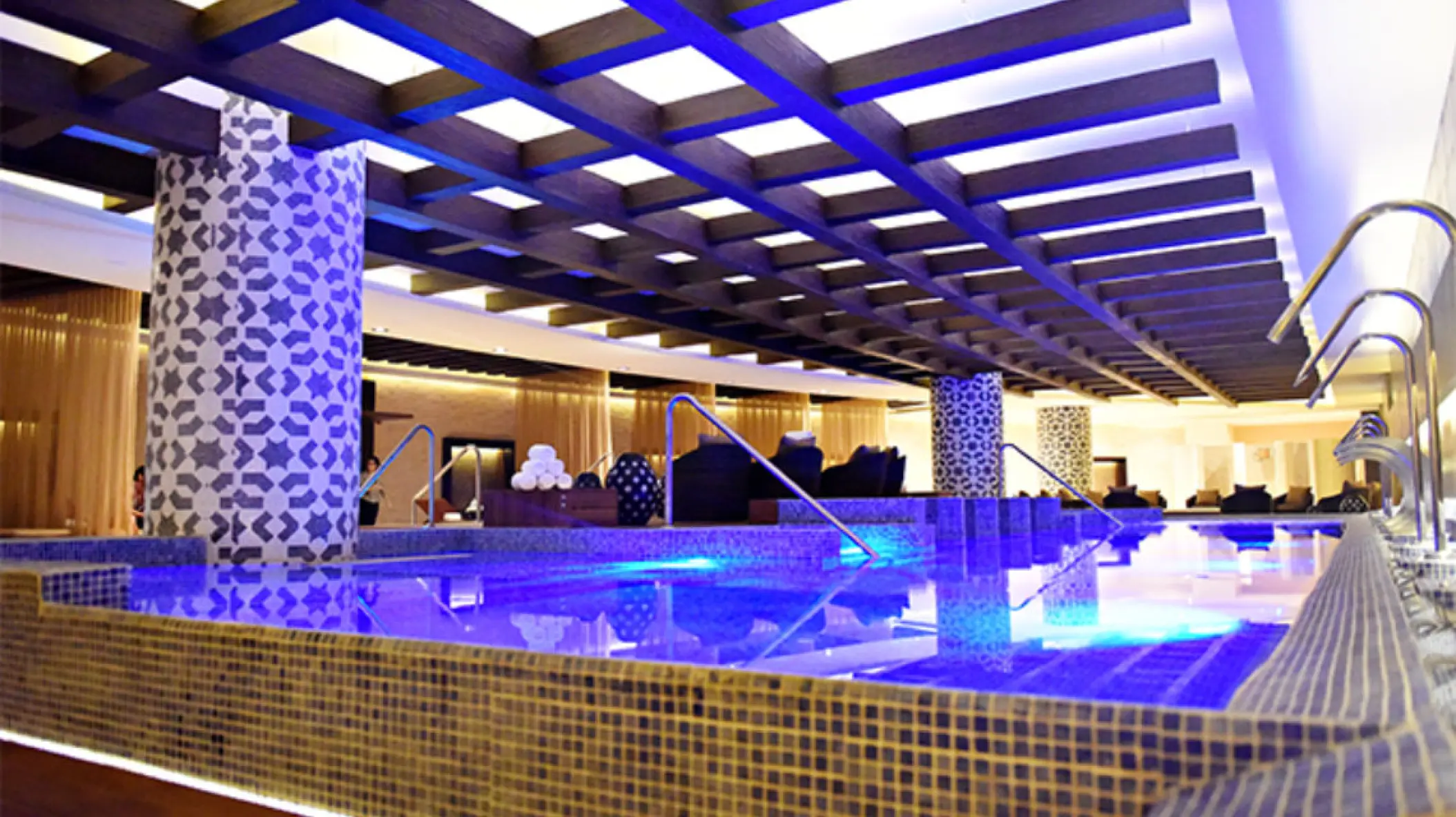 Indoor hydrotherapy pool with blue lighting and tiled columns at Royalton Riviera Cancun