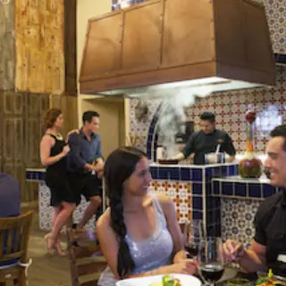 Couples dining at a tiled restaurant with an open kitchen at Royalton Riviera Cancun