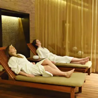 Two women in white robes relaxing on lounge chairs at the Royalton Riviera Cancun spa, Cancun