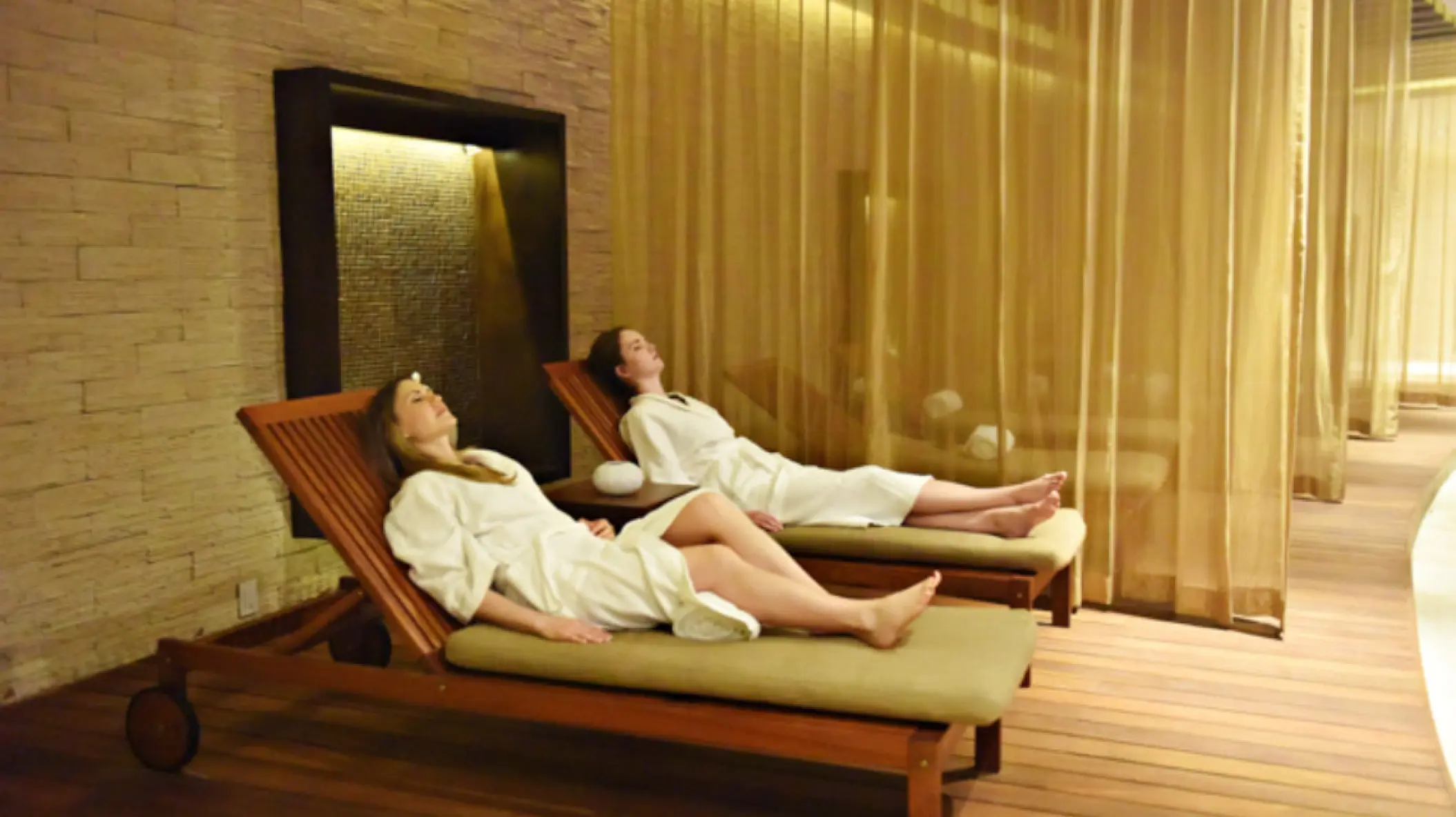 Two women in white robes relaxing on lounge chairs at the Royalton Riviera Cancun spa, Cancun
