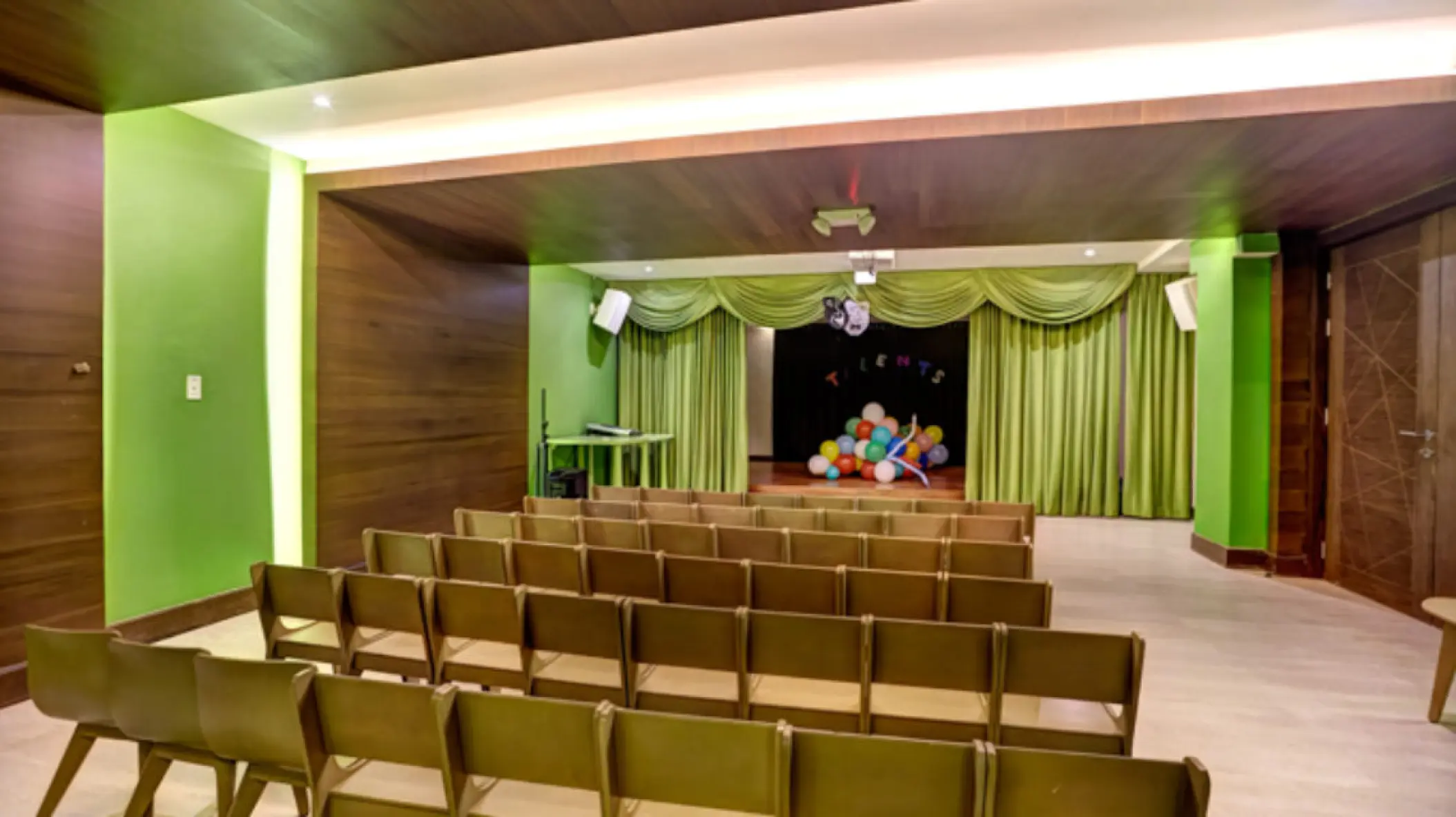 Theater and kids club with rows of wooden seating and a small stage at Royalton Riviera Cancun