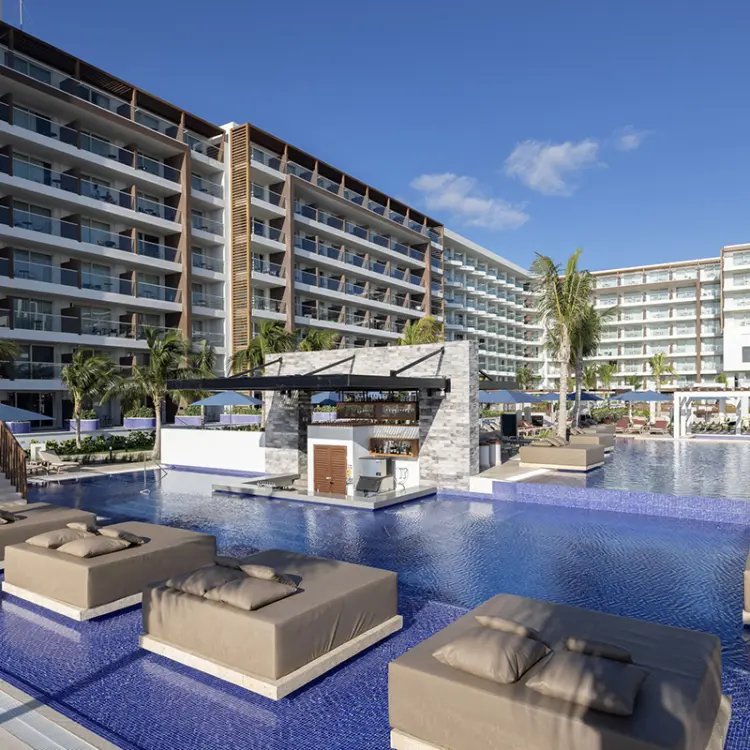 Outdoor swimming pool with submerged lounge beds and swim-up bar at Royalton Splash Riviera Cancun