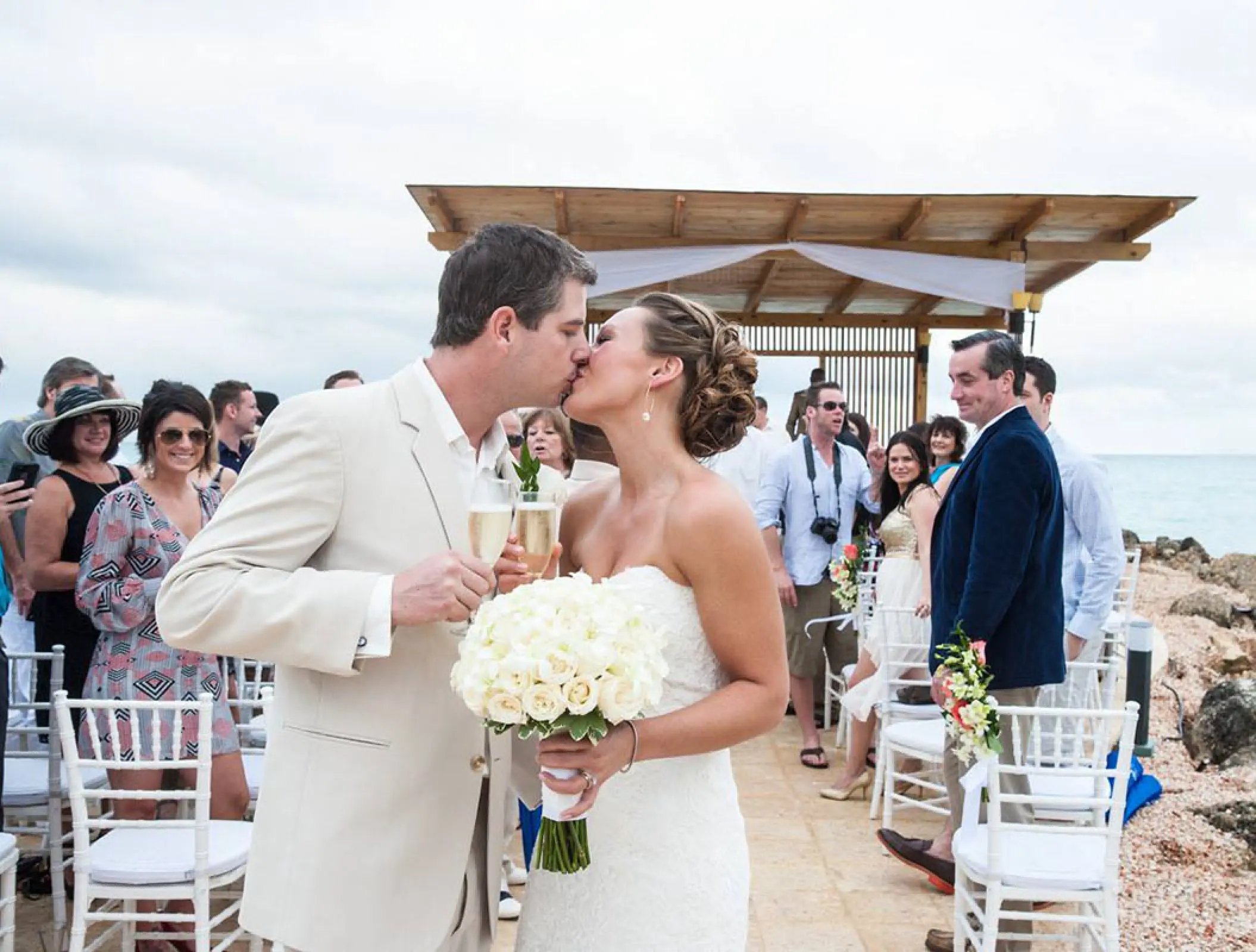 The bride and groom kissing while holding champagne at Royalton Blue Waters, Montego Bay