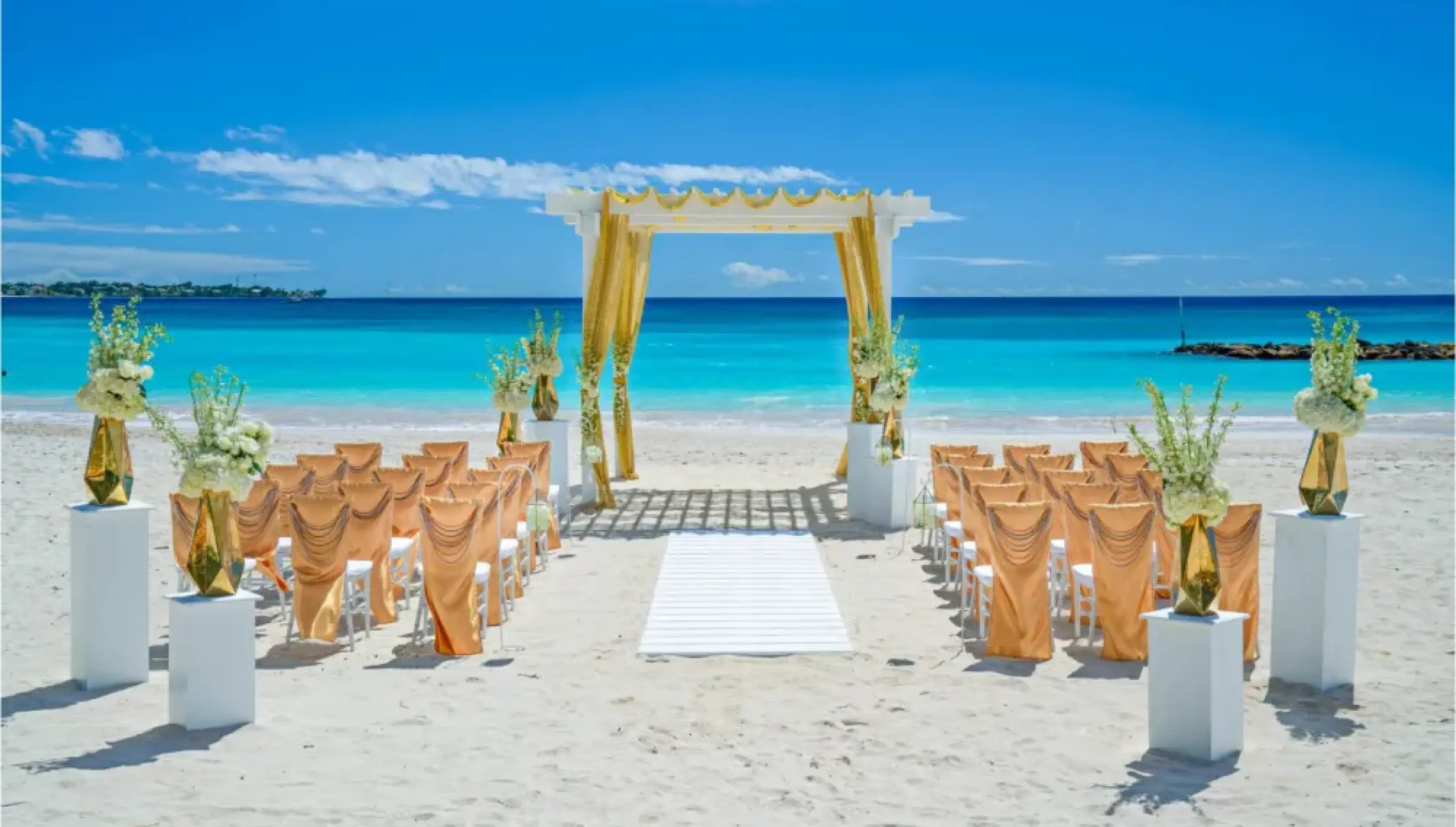 Beachfront wedding ceremony with a gold-draped pergola at Sandals Montego Bay, Jamaica