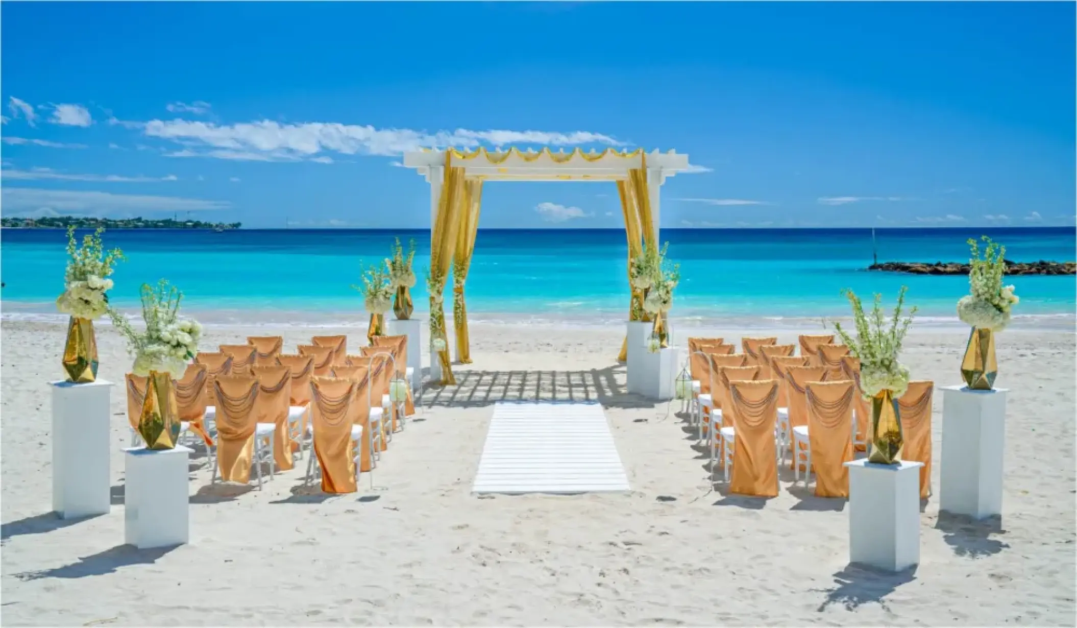 Beachfront wedding ceremony with a gold-draped pergola at Sandals Montego Bay, Jamaica