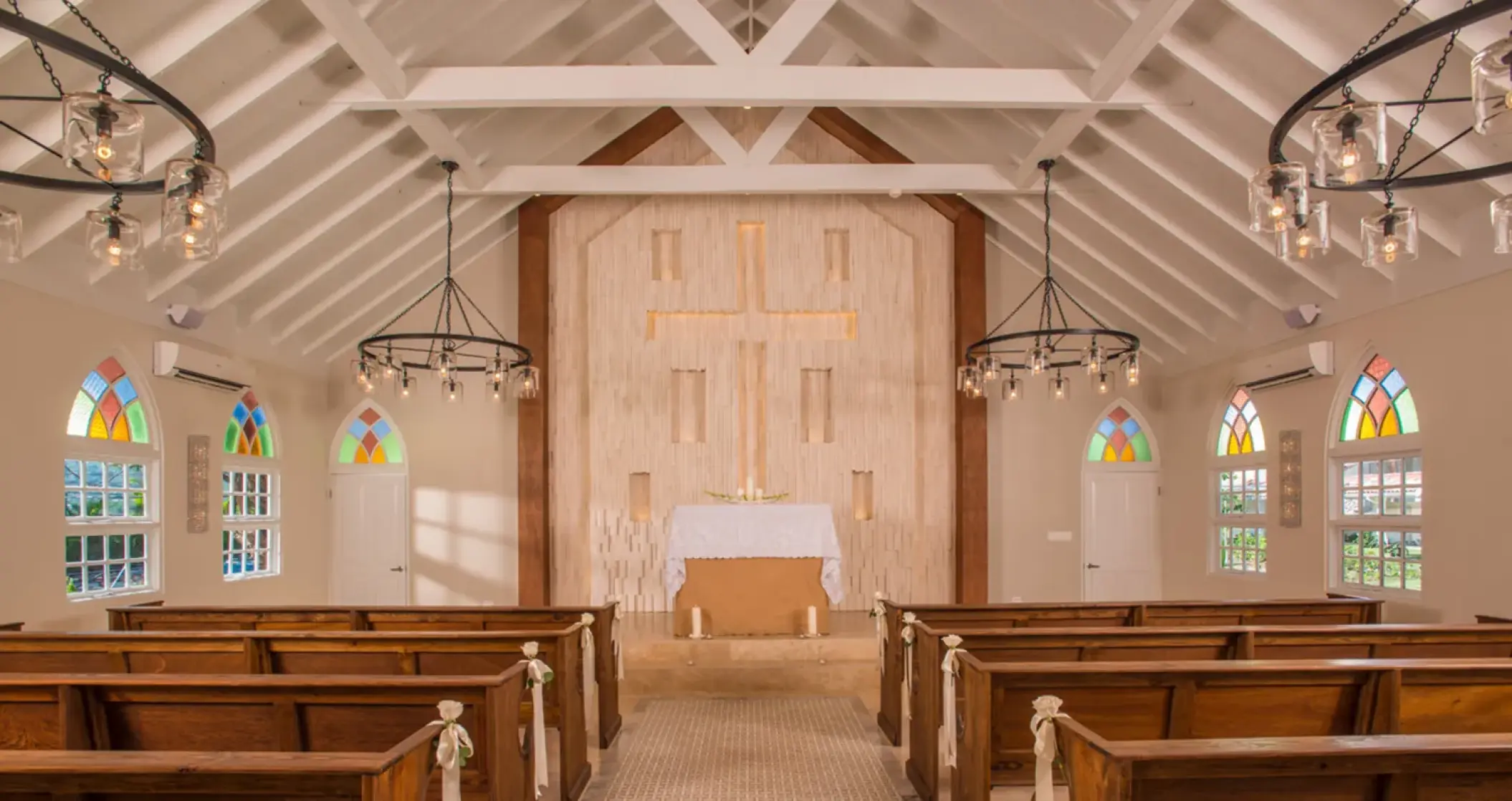 Indoor wedding ceremony chapel with wooden pews and stained glass at Sandals Montego Bay