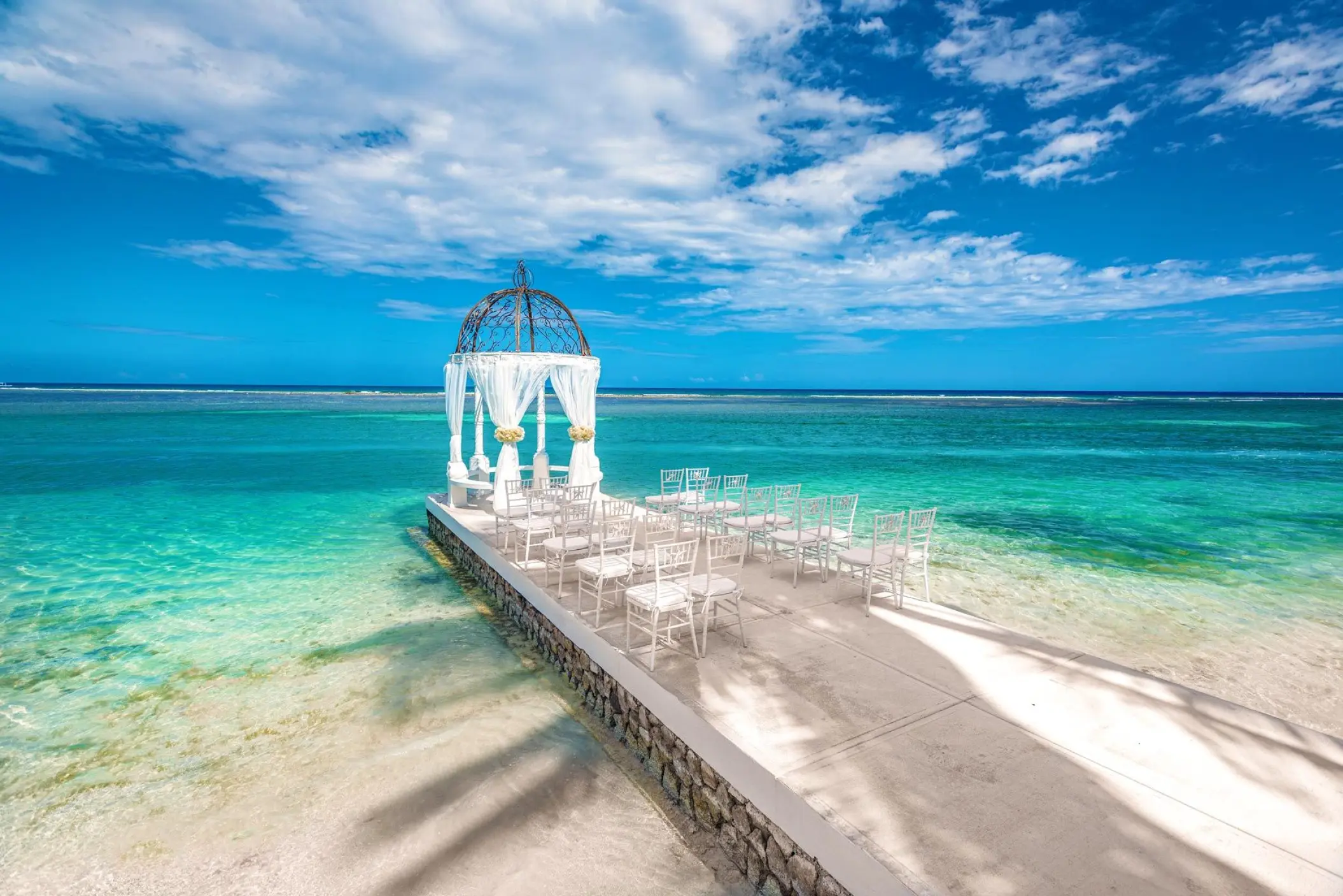 Overwater wedding ceremony gazebo and white chairs at Sandals Montego Bay, Montego Bay