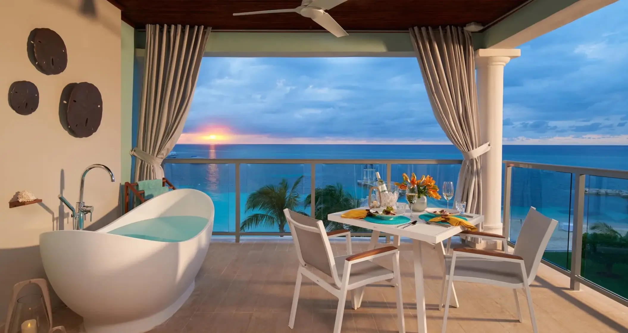 Sandals Montego Bay oceanfront balcony with a soaking tub and dining set at sunset, Montego Bay