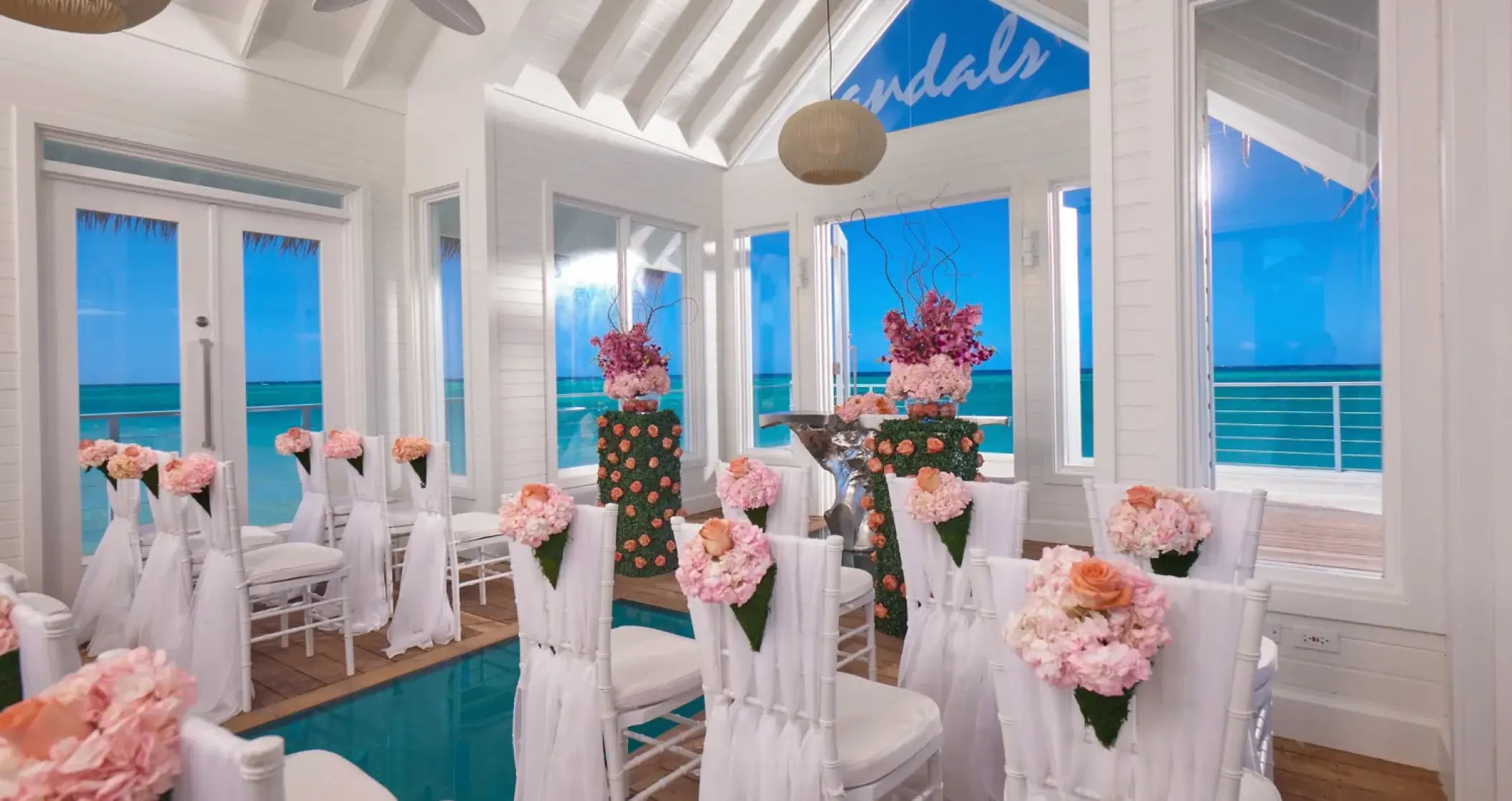 Overwater chapel wedding ceremony with pink floral décor at Sandals Montego Bay, Montego Bay
