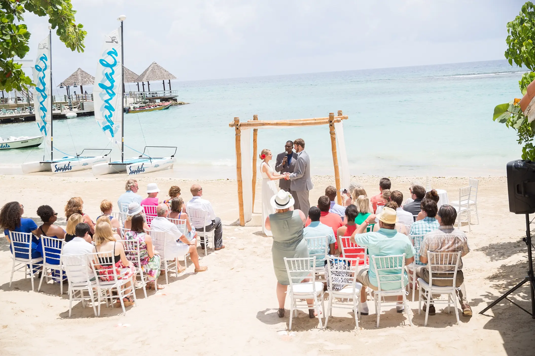 Beachfront wedding ceremony with a bamboo arch at Sandals Ochi, Ocho Rios