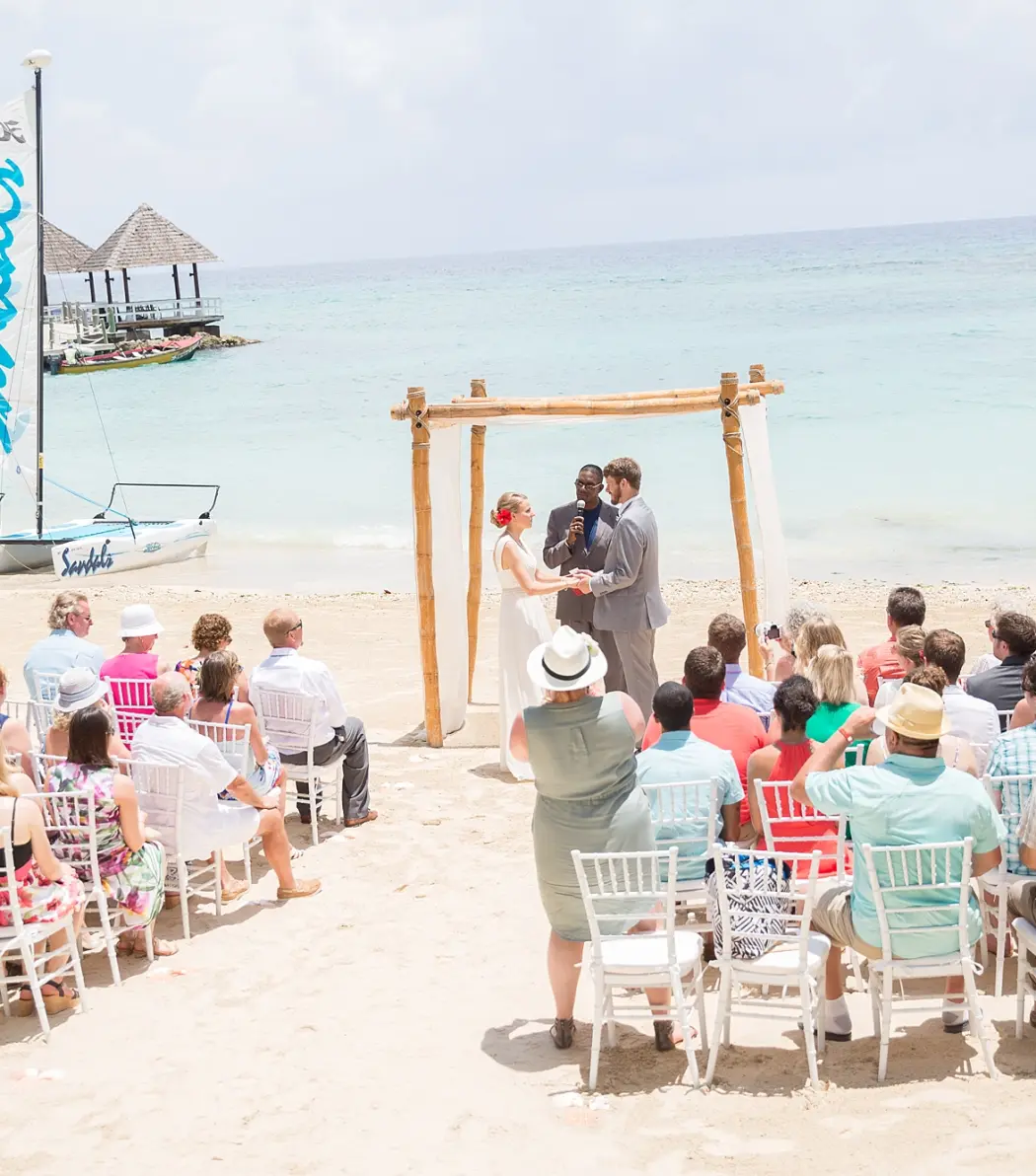 Beachfront wedding ceremony with a bamboo arch at Sandals Ochi, Ocho Rios