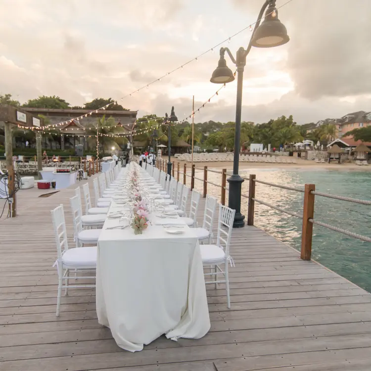 Long table wedding reception on a wooden pier at Sandals Ochi, Ocho Rios