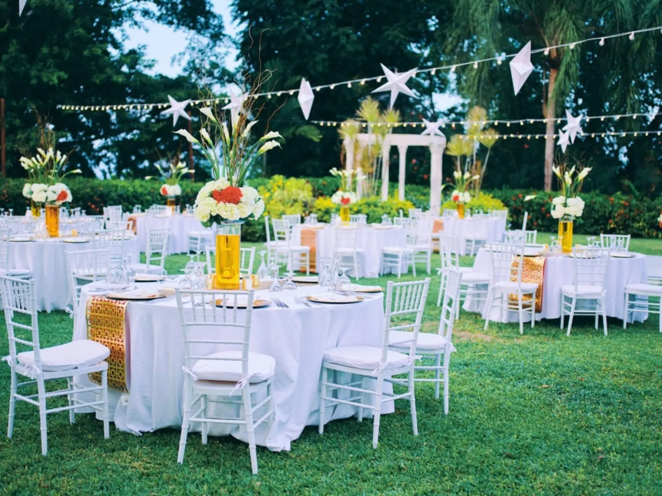 Outdoor garden wedding reception with white tables and hanging stars at Sandals Ochi, Ocho Rios