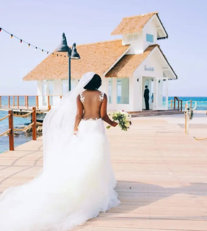 Bride walking toward the overwater wedding chapel at Sandals Ochi, Ocho Rios