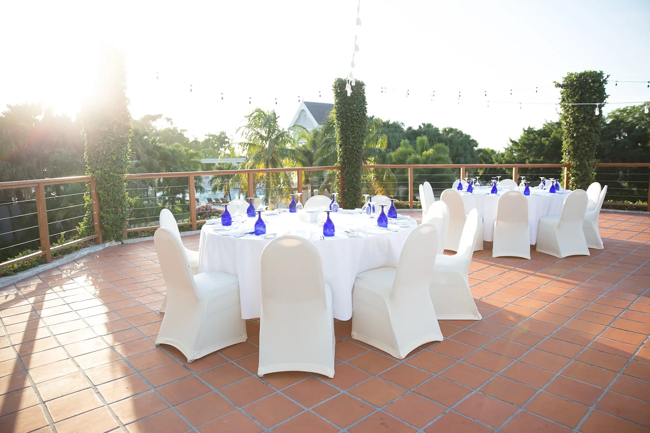 Outdoor wedding reception setup with round tables on a terrace at Sandals Ochi, Ocho Rios