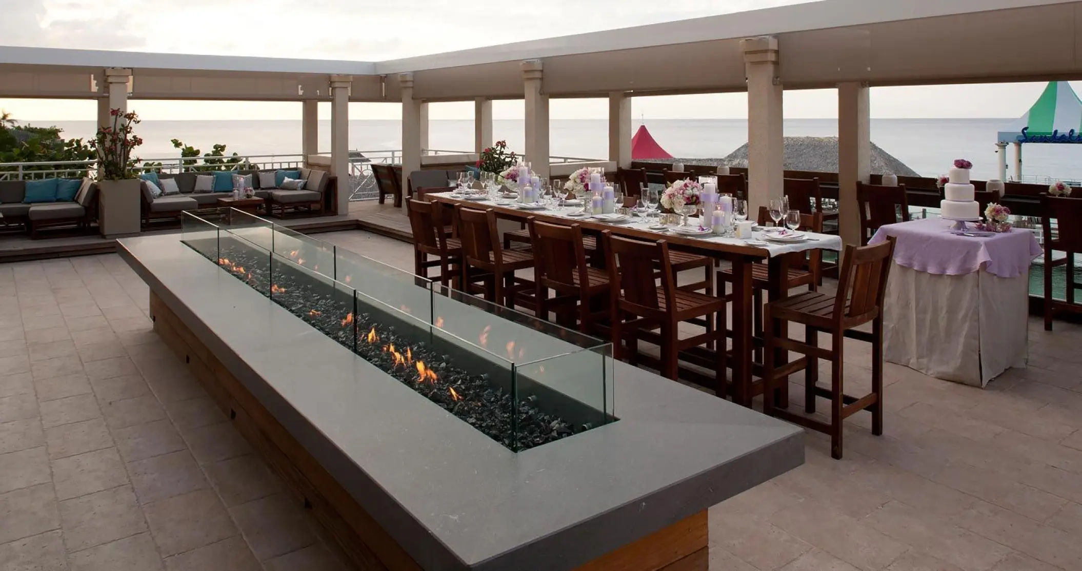 Rooftop wedding reception at Sandals Ochi, Ocho Rios featuring a long banquet table and fire pit overlooking the ocean