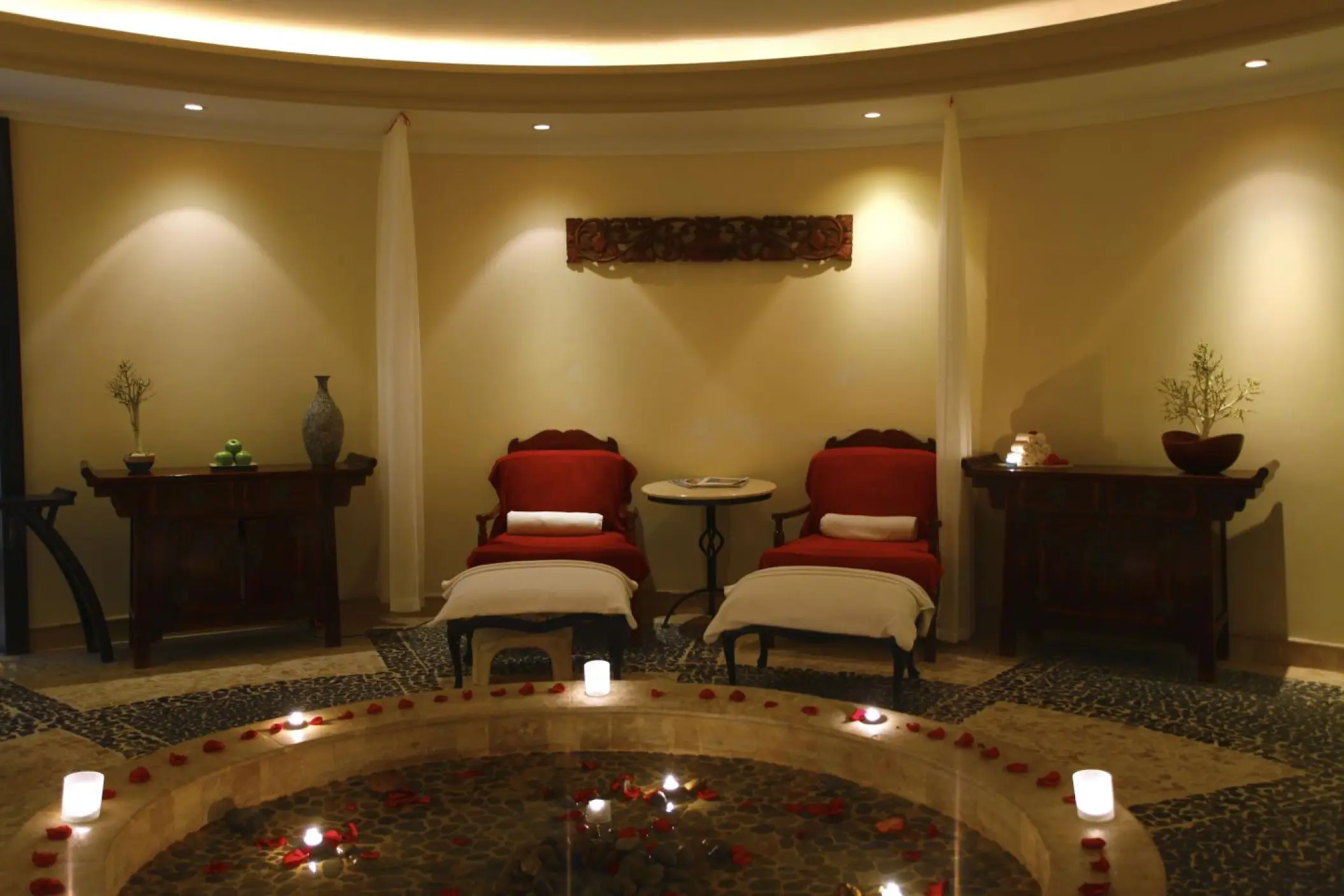 Spa lounge with red armchairs and candlelit water feature at Sandos Cancun, Cancun