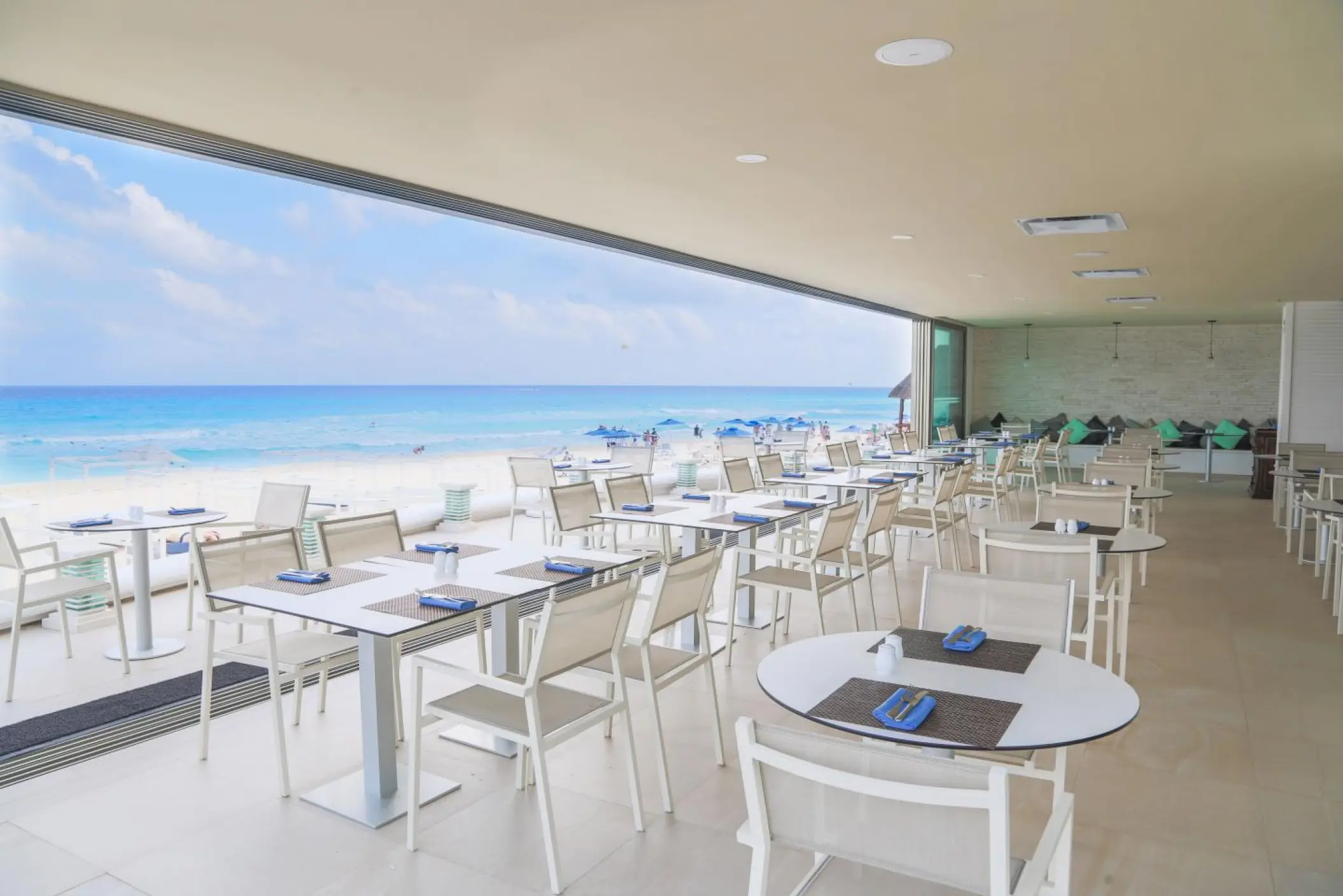 Open-air restaurant with white tables overlooking the beach at Sandos Cancun