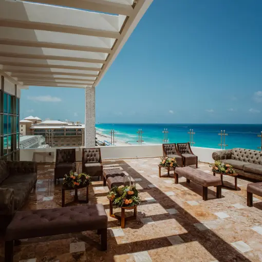 Rooftop terrace lounge with tufted sofas and turquoise ocean views at Sandos Cancun, Cancun