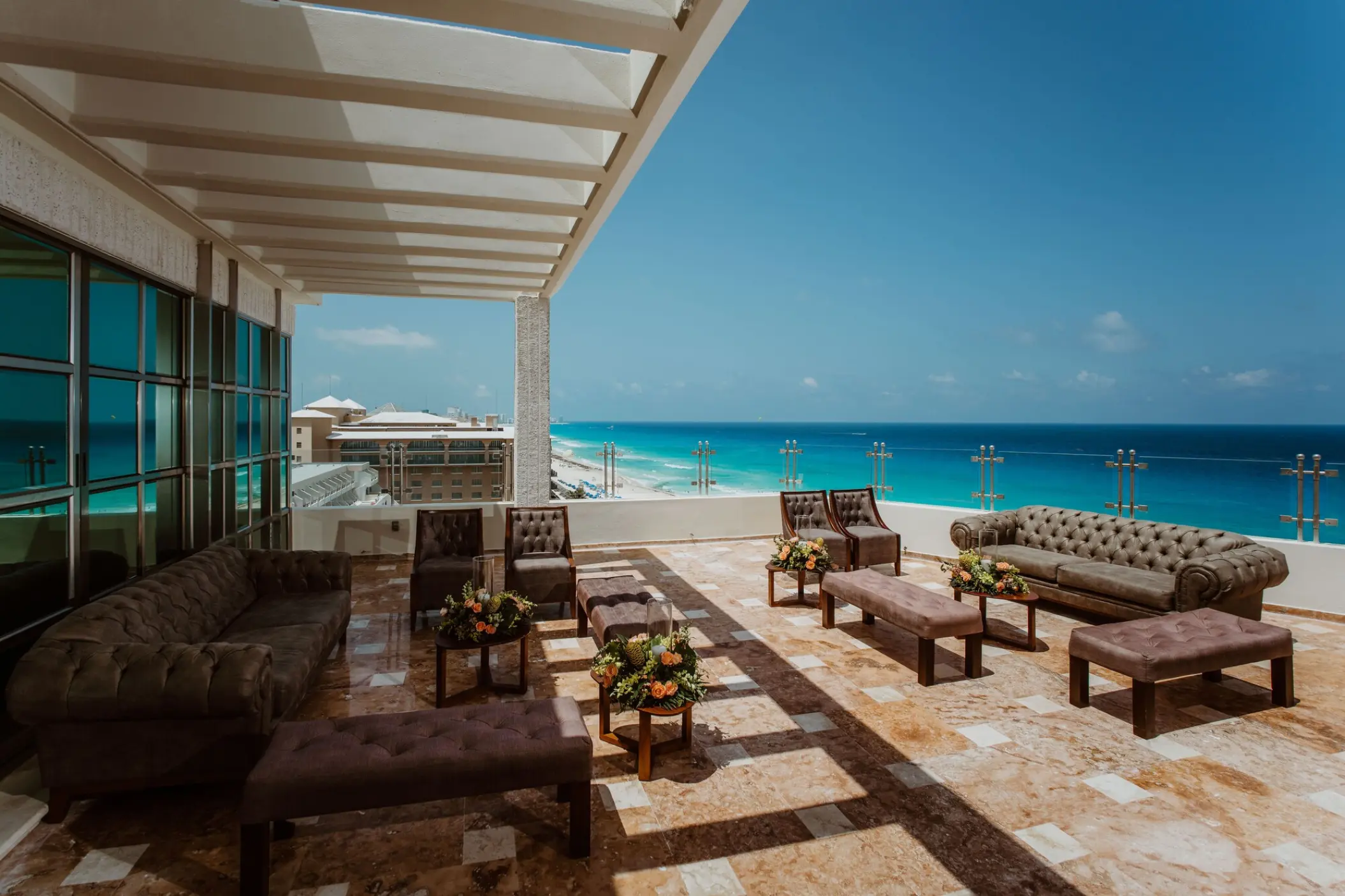 Rooftop terrace lounge with tufted sofas and turquoise ocean views at Sandos Cancun, Cancun