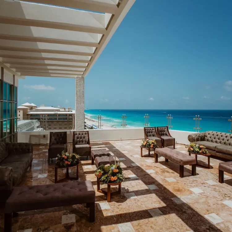 Rooftop terrace lounge with tufted sofas and turquoise ocean views at Sandos Cancun, Cancun