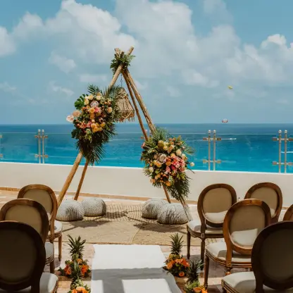 Teepee wedding ceremony arch on a terrace overlooking the ocean at Sandos Cancun, Cancun