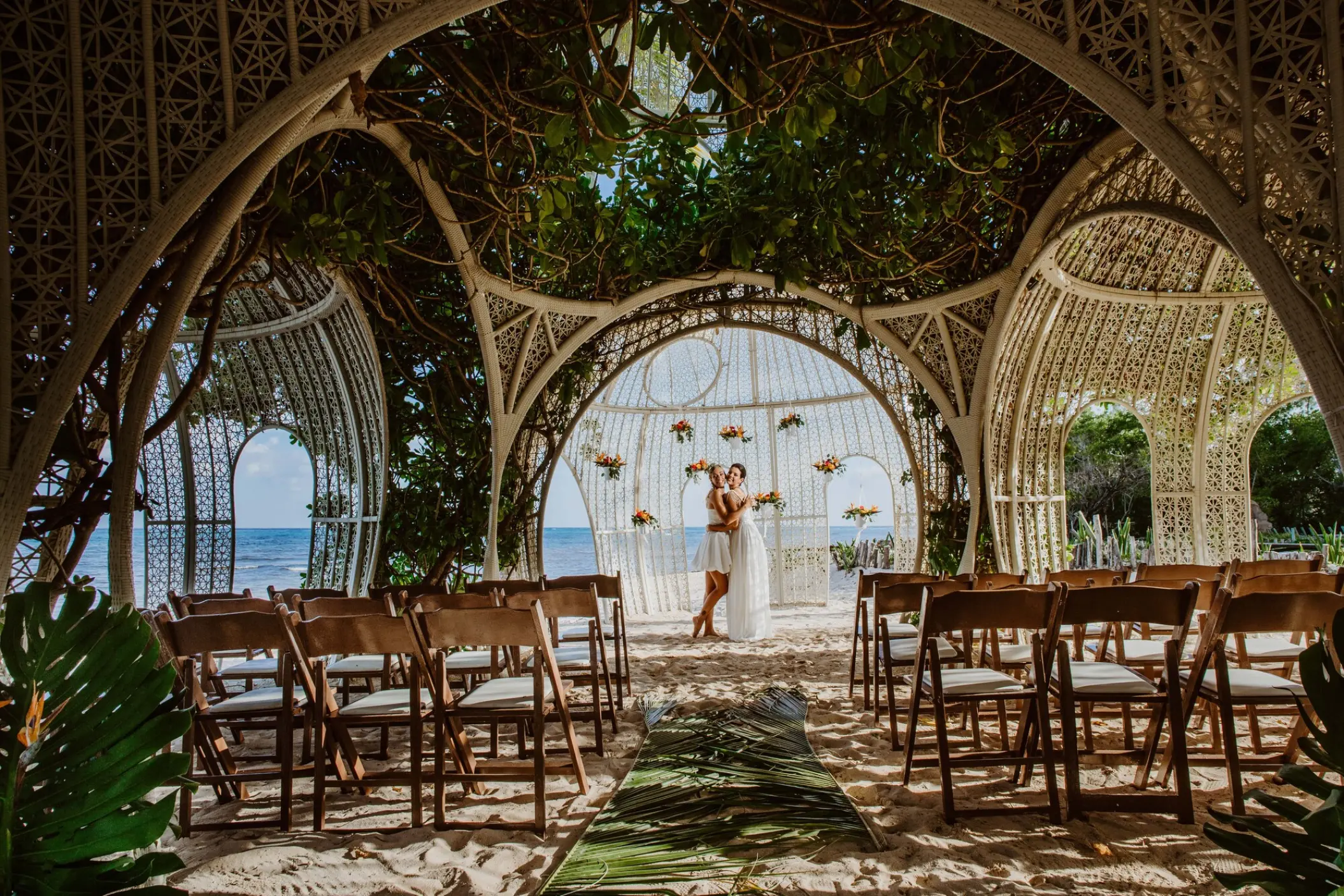 Couple embracing under an ornate beach gazebo wedding ceremony setup at Sandos Caracol, Playa Del Carmen