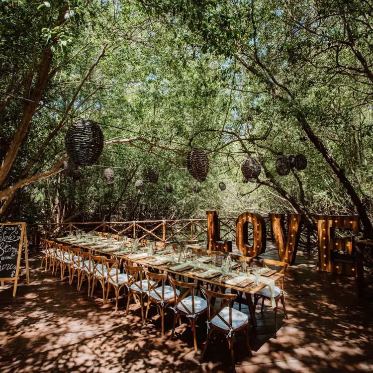 Jungle wedding reception with long wooden tables and LOVE marquee letters at Sandos Caracol, Playa Del Carmen
