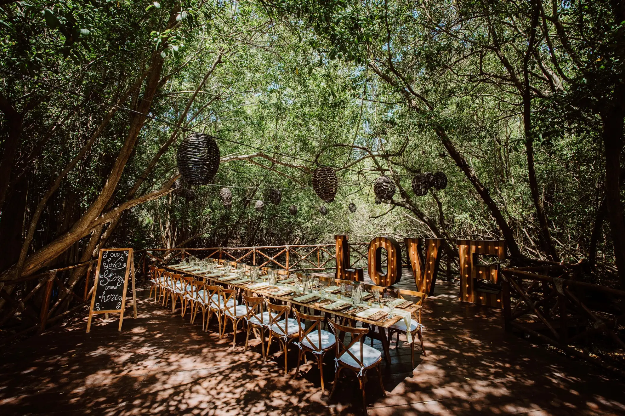 Jungle wedding reception with long wooden tables and LOVE marquee letters at Sandos Caracol, Playa Del Carmen