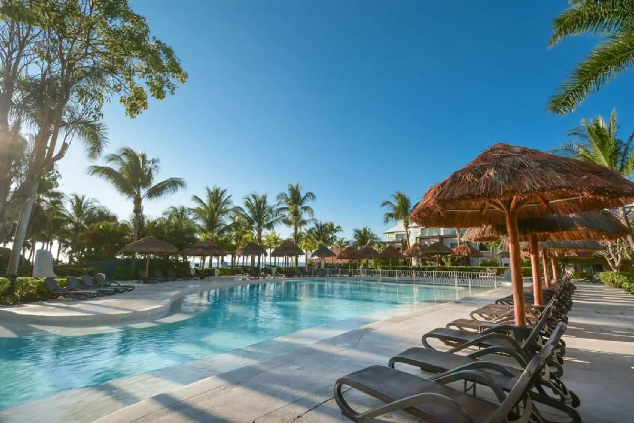 Sandos Caracol outdoor swimming pool with palapas and lounge chairs, Playa Del Carmen
