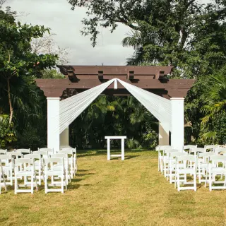 Garden wedding ceremony setup with white chairs and a wooden gazebo at Sandos Playacar, Playa Del Carmen