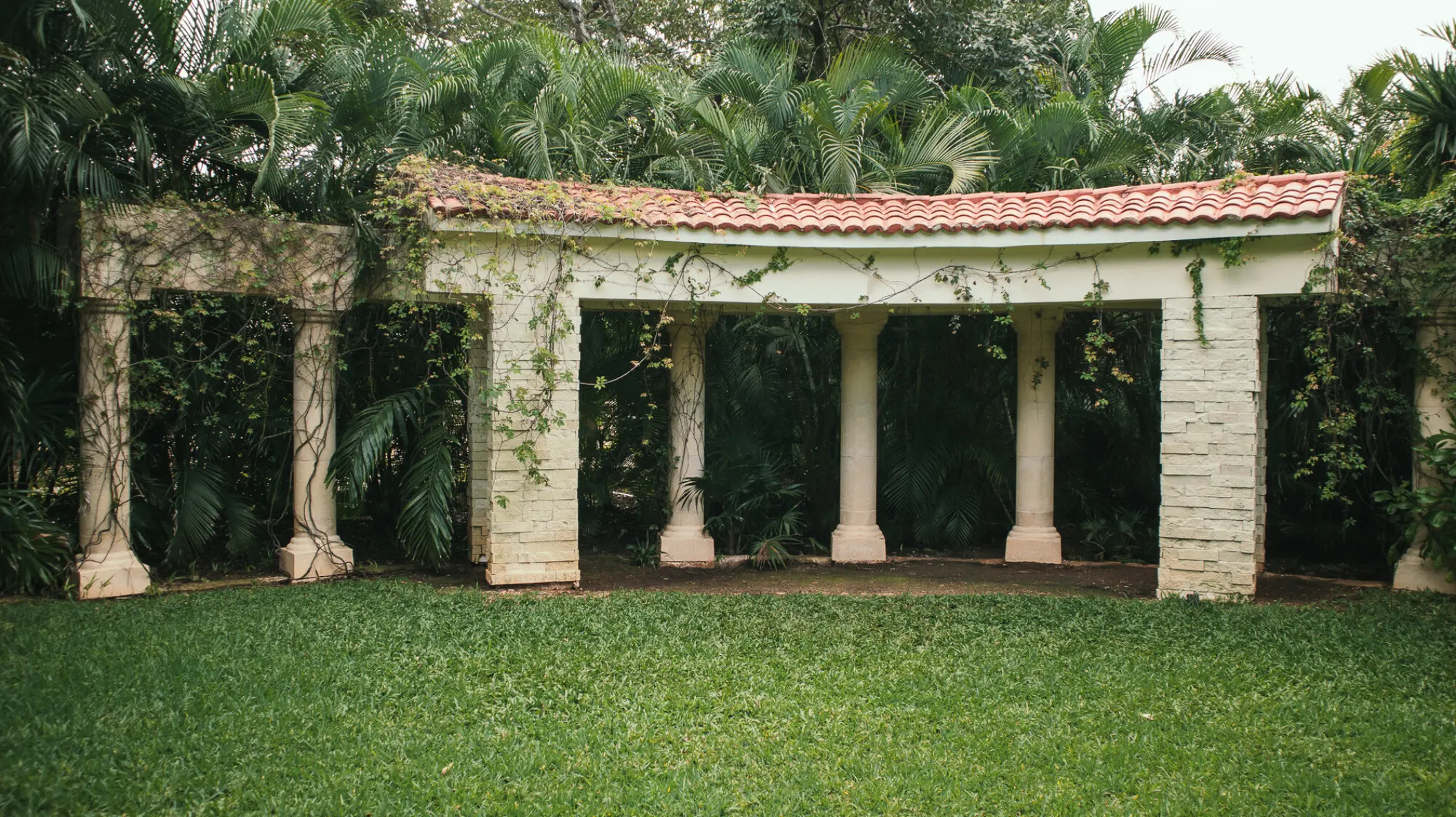 Secret Garden wedding venue with stone columns and lush greenery at Sandos Playacar, Playa Del Carmen