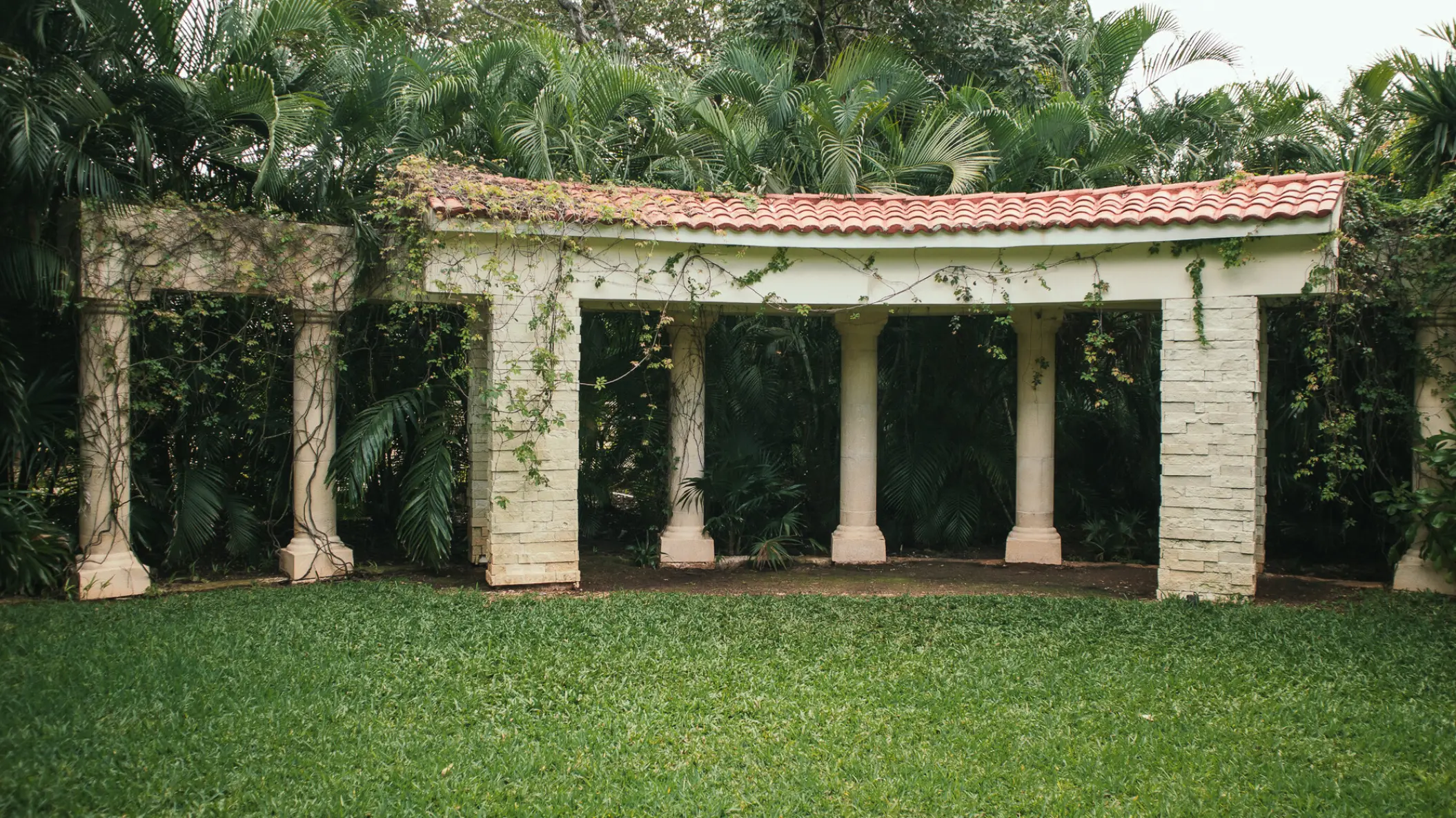 Secret Garden wedding venue with stone columns and lush greenery at Sandos Playacar, Playa Del Carmen