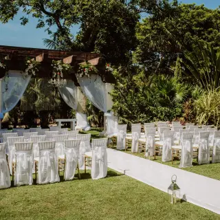 Garden wedding ceremony setup with a draped wooden pergola at Sandos Playacar, Playa Del Carmen