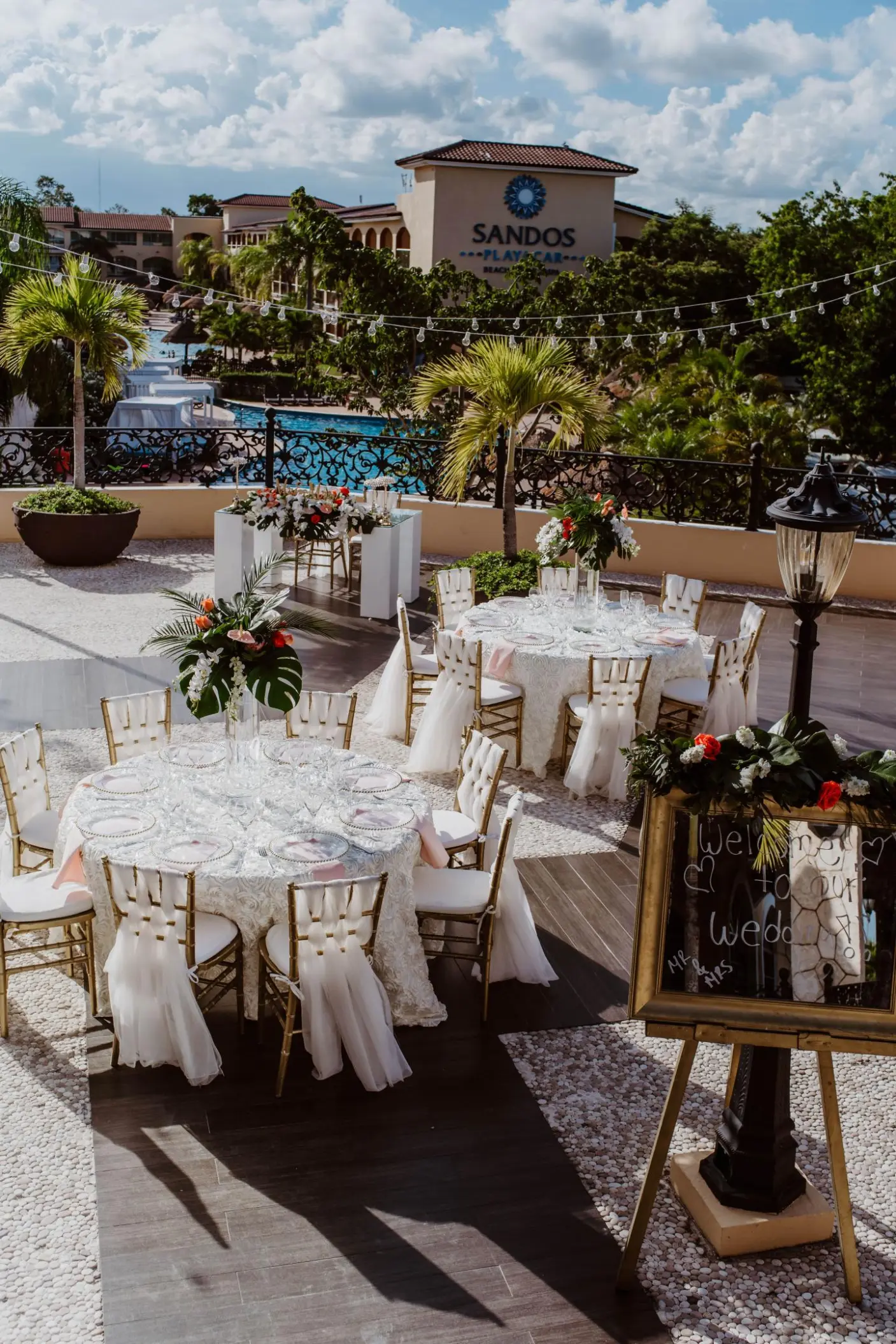 Terrace wedding reception with floral centerpieces and white linens at Sandos Playacar, Playa Del Carmen