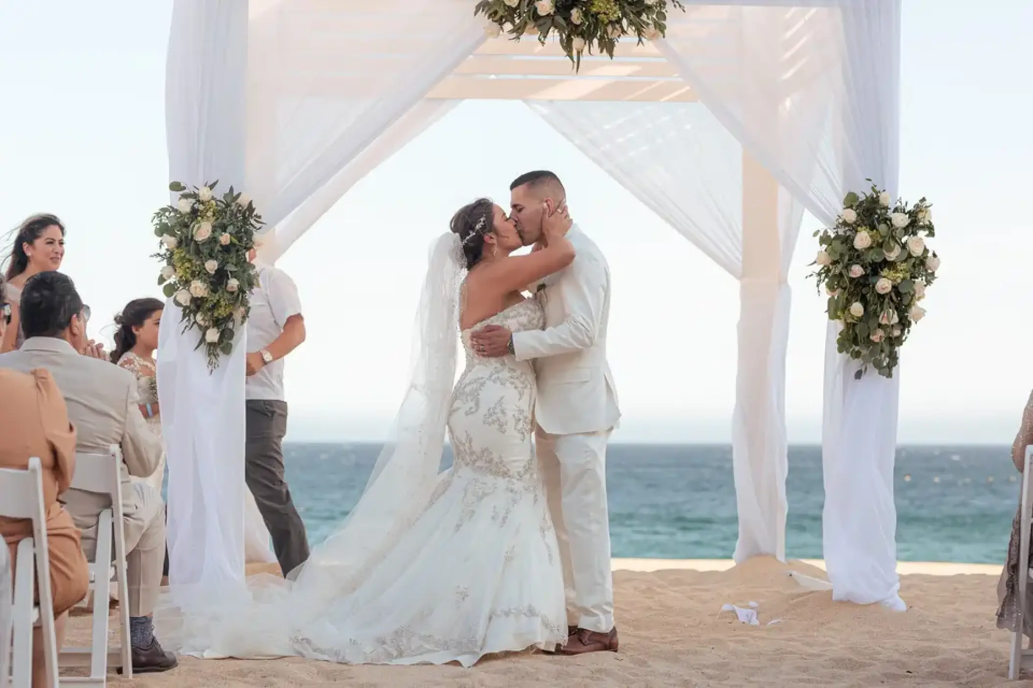 Bride and groom sharing a first kiss during a beach ceremony at Sandos Finisterra, Cabo San Lucas
