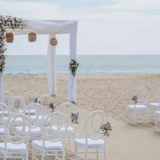 Beachfront wedding ceremony with white huppah and chairs at Sandos Finisterra, Cabo San Lucas
